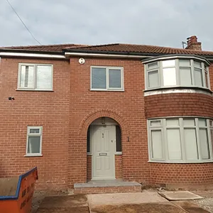 a red brick house with a blue dumpster in front of it