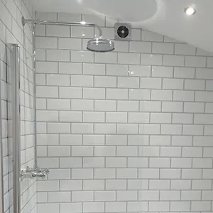 a white tiled bathroom with a tub and shower